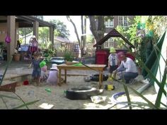 a man and two children are playing in the sand at a backyard play area with toys