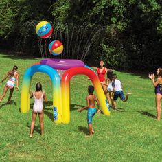 children playing in an inflatable pool on the grass with balloons and water toys