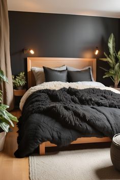 a bed with black blankets and pillows in a dark room next to potted plants