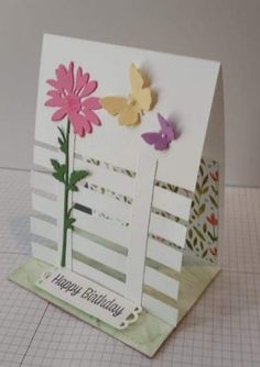 a birthday card with flowers and butterflies on the front, sitting on top of a piece of paper