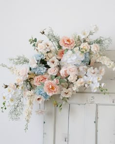 a bunch of flowers that are on top of a white door frame, against a white wall