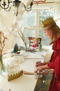 a woman in a red dress is painting a christmas scene on a table with other decorations