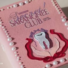 a pink box with a tooth on it and pearls around the edges that says sparkle club