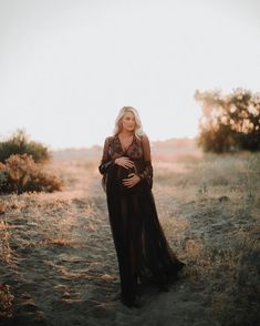 a woman standing in the middle of a field with her belly wrapped around her waist