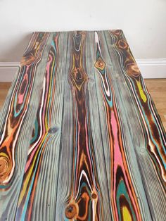 a wooden table with multicolored paint on it's surface in a room