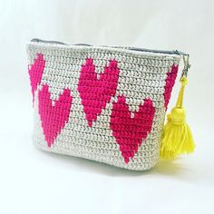 a crocheted purse with hearts on it and a tassel hanging from the front