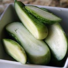 a white bowl filled with cucumbers on top of a table