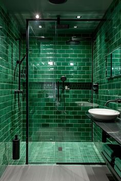 a green tiled bathroom with a sink and shower