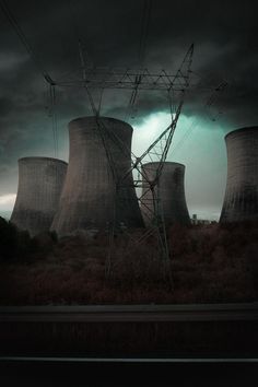 an image of nuclear power plant with storm clouds in the sky behind it and grass below