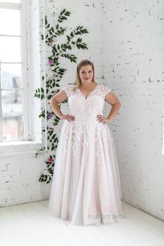 a woman standing in front of a window wearing a wedding dress