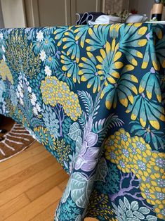 a blue and yellow table cloth with flowers on it in front of a wooden floor