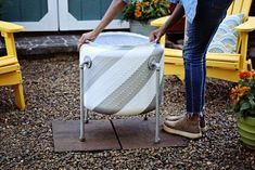 a woman standing next to a white cooler on top of a wooden floor in front of yellow chairs