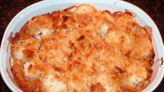 a casserole dish in a white bowl on a brown counter top with meat and cheese