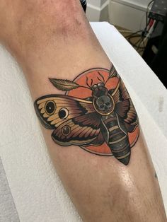 a moth tattoo on the leg