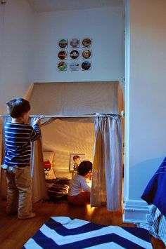 two children are playing in their room with the curtains open and lights on at night