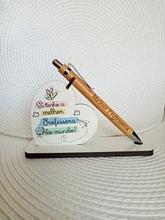 a wooden pen sitting on top of a notepad next to a paper heart shaped magnet