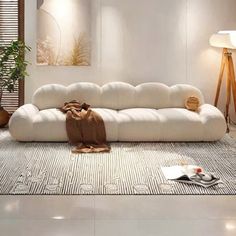 a white couch sitting on top of a rug in a living room next to a lamp