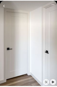 an empty room with white walls and wooden flooring is shown in this image, there are black handles on the doors