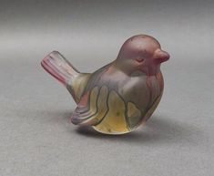 a glass figurine of a bird on a gray surface with its wings spread