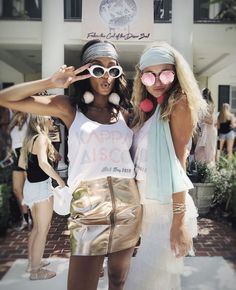 two women standing next to each other in front of a building with sunglasses on their faces