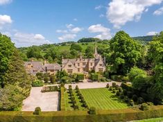 an aerial view of a large house surrounded by lush green trees and hedges in the foreground