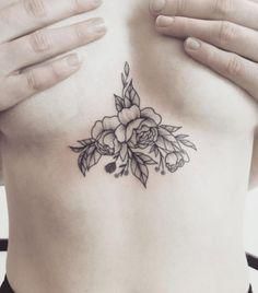 a woman's chest with flowers and leaves tattooed on the side by her hands