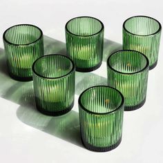 six green glass cups sitting on top of a table