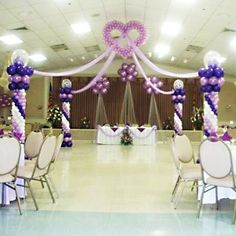 an indoor event decorated with purple and white balloons