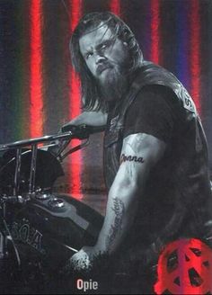 a man with long hair sitting on a motorcycle