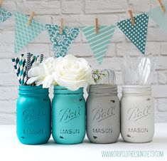 four mason jars are lined up in front of a brick wall with bunting flags