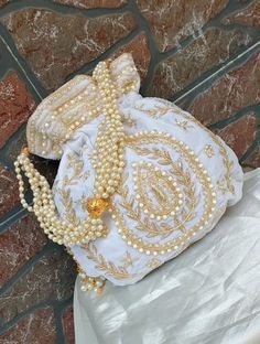 a white purse sitting on top of a stone floor next to a bag with pearls hanging from it