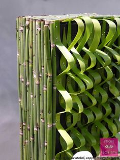 a close up of a bamboo structure with green ribbons on it's sides and the bottom