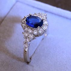 a blue and white diamond ring sitting on top of a box with its lid open