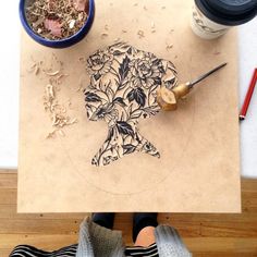 a person standing in front of a wooden cutting board with a flower design on it