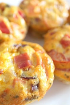 several mini muffins with bacon and cheese on them sitting on a white plate