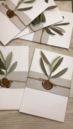 four cards with olives tied to them on top of a wooden table next to two envelopes