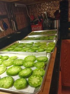 several trays filled with green peppers sitting on top of a counter next to an oven