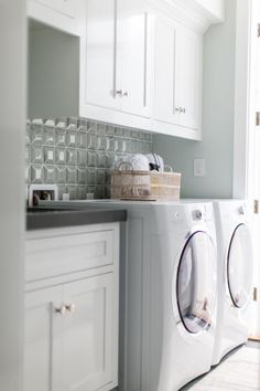 a washer and dryer in a room with white cabinets on either side of the washer