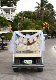 a bride and groom are riding in the back of a golf cart decorated with wedding decorations