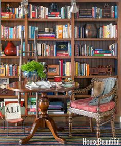 a room filled with lots of books on top of a wooden book shelf next to a table