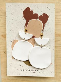 a pair of white and gold earrings on top of a piece of paper that says hello asito