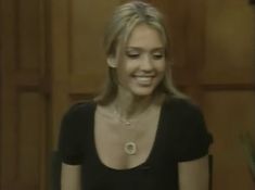 a woman standing in front of a wooden door with her eyes closed and wearing a necklace