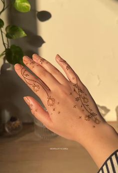 a woman's hand with tattoos on it and a potted plant in the background