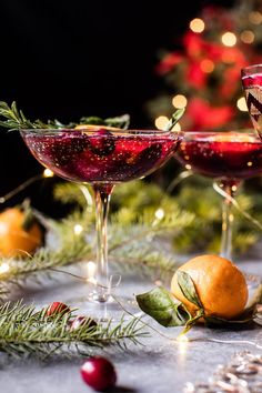 two glasses filled with red liquid sitting on top of a table next to christmas decorations