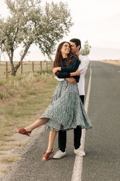 a man and woman are hugging on the road