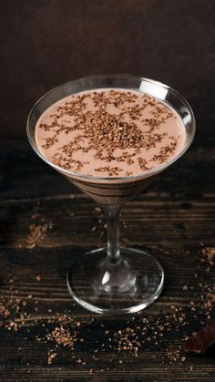 a dessert is garnished with sprinkles in a glass on a wooden table