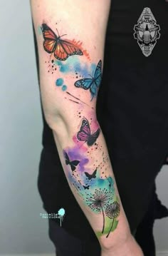 a woman's arm with watercolor tattoos on it and butterflies flying over the flowers