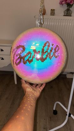 a hand holding a disco ball in front of a white radiator heater