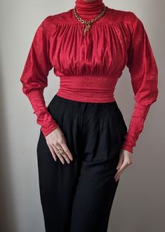 Sublime vintage blouse dating from the 1980s, a creation by the French luxury fashion house Chantal Thomass. It's an incredible model, with a beautiful, passionate red color that will illuminate all skin tones. Its cut is spectacular, with its belted waist and high collar with a very aristocratic look. The sleeves are cut in a lamb shape, with slightly puffed shoulders and tightened cuffs. Magnificent pleated work decorates the entire bust, meticulous artisanal work. It closes with an invisible Retro Red Top For Party, Retro Red Party Tops, Red Retro Party Tops, Retro Red Party Top, Red Retro Party Top, Red Retro Formal Tops, Retro Red Formal Tops, Vintage Party Blouse With Puff Sleeves, Vintage Red Long Sleeve Blouse