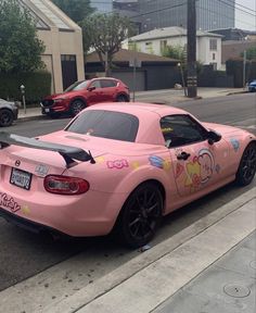 a pink sports car parked on the side of the road with stickers all over it